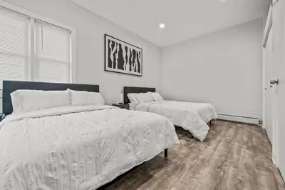 a white bedroom with two beds and a window at Spacious 3-Bedroom Apartment near NYC - 15min to Times Square, Empire State Building, Central Park, Statue of Liberty in Jersey City