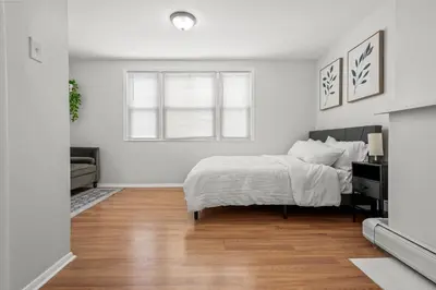 a white bedroom with a bed and a couch at Spacious 3-Bedroom Apartment near NYC - 15min to Times Square, Empire State Building, Central Park, Statue of Liberty in Jersey City