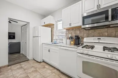 a kitchen with white cabinets and a white stove top oven at Spacious 3-Bedroom Apartment near NYC - 15min to Times Square, Empire State Building, Central Park, Statue of Liberty in Jersey City