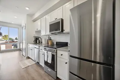 a kitchen with white cabinets and a stainless steel refrigerator at The Commons on Ludlow in Philadelphia