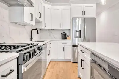 a kitchen with white cabinets and a stainless steel refrigerator at Modern Luxury 3BR 2BA 10 minutes to NYC in Weehawken