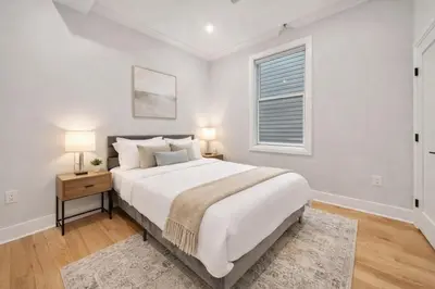 a white bedroom with a large bed and a window at Modern Luxury 3BR 2BA 10 minutes to NYC in Weehawken