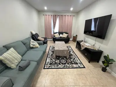 a living room with a blue couch and a flat screen tv at Modern Oasis in Bayonne