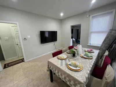 a dining room with a table and chairs and a television at Modern Oasis in Bayonne