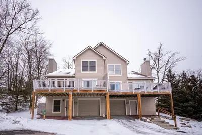 a house with a wrap around deck in the snow at Luxury House in Pocono Mountains in Tannersville