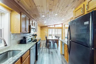 a kitchen with a black refrigerator and a table at Hot Tub, Dock, Pool Table! Lakefront Poconos Haven in White Haven