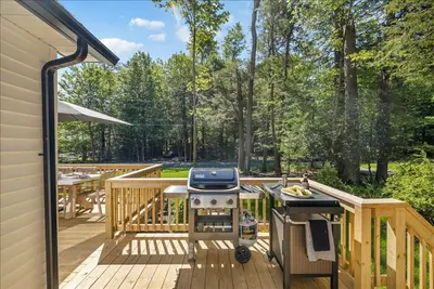 a wooden deck with a grill and a table at Luxury Hot Tub Sauna Game Room Dog Friendly in Albrightsville