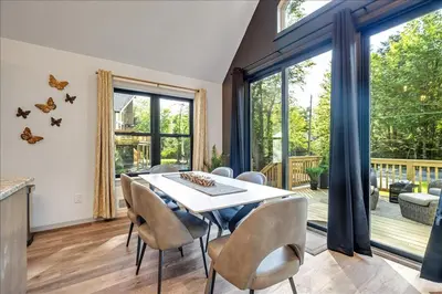 a dining room with a table and chairs and large windows at Luxury Hot Tub Sauna Game Room Dog Friendly in Albrightsville
