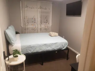 a bedroom with a bed and a window and a tv at Orchard Room by the Airport - Shared Space in Darby