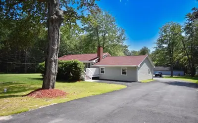 a house with a tree in front of a driveway at Cozy home away from home in Tobyhanna