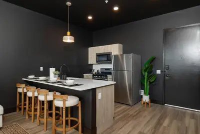 a kitchen with a island with bar stools and a refrigerator at Cozy 1 King BR, Gym, Free Parking, 8mins Train in East Orange