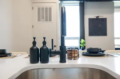 a kitchen with a sink with bottles on the counter at 2BR, King Bd, Free Prkn, Gym, NYC View, 8min Train in East Orange