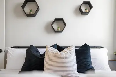 a group of pillows on a bed with two mirrors at 2BR, King Bd, Free Prkn, Gym, NYC View, 8min Train in East Orange