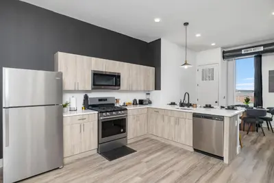 a kitchen with stainless steel appliances and wooden cabinets at 2BR, King Bd, Free Prkn, Gym, NYC View, 8min Train in East Orange