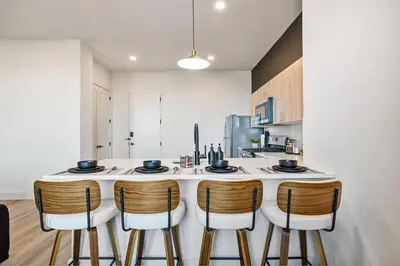 a kitchen with a large white counter with chairs around it at 2BR, King Bd, Free Prkn, Gym, NYC View, 8min Train in East Orange