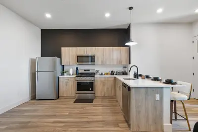 a kitchen with stainless steel appliances and wooden cabinets at 2BR, King Bd, Free Prkn, Gym, NYC View, 8min Train in East Orange