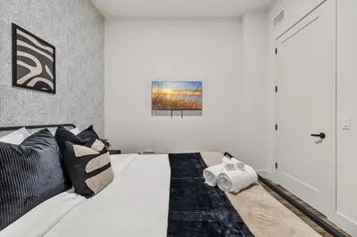 a bedroom with a large white bed with black pillows at King Bd, Free Prkn, NYC View, 8min Train in East Orange