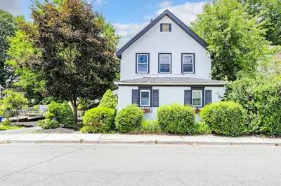 a white house with bushes in front of a street at Two-Bedroom Home 25 min to NYC Free parking-UNIT-1 in Teaneck
