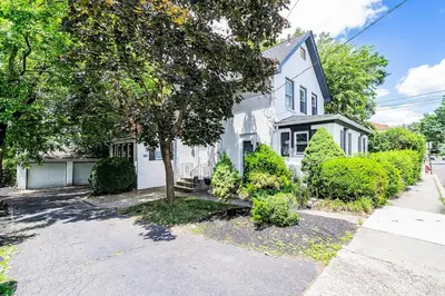 a white house with a tree in front of it at Two-Bedroom Home 25 min to NYC Free parking-UNIT-1 in Teaneck