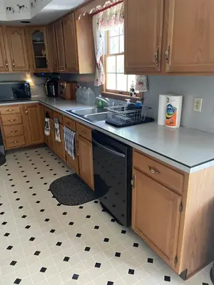 a kitchen with wooden cabinets and a black dishwasher at Top floor modern country home in Northampton