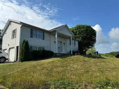 a house on a grassy hill with a car at Top floor modern country home in Northampton