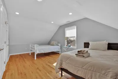 a white bedroom with a bed and a chair at Oceanfront Villa - Panoramic NYC Views - Luxury Home in Keansburg