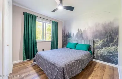 a bedroom with a bed and a painting on the wall at Whimsical Wilderness Lodge in Tobyhanna