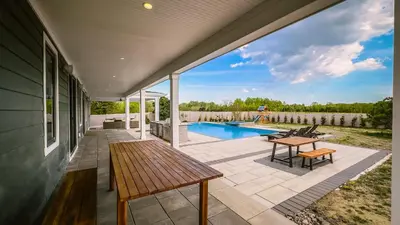 an outdoor patio with a table and a pool at Modern Farm Estate Close To Six Flags & Vineyard in Cream Ridge