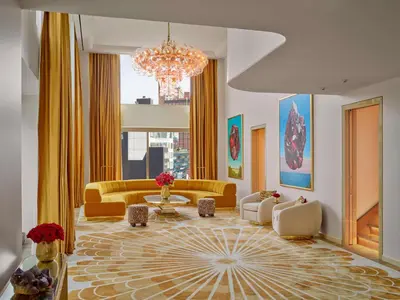 a living room with yellow furniture and a chandelier at Faena New York in New York