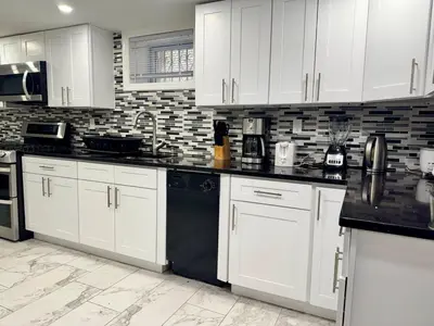 a kitchen with white cabinets and black appliances at 2-Bedroom Sleeps 6 Stay Near EWR & American Dream in Newark
