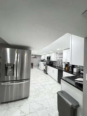 a large kitchen with white cabinets and stainless steel appliances at 2-Bedroom Sleeps 6 Stay Near EWR & American Dream in Newark