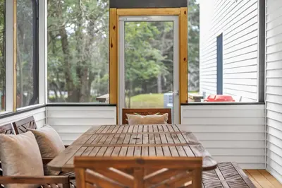 a porch with a wooden table and chairs and windows at Luxury Hot Tub Game Room and More in Albrightsville