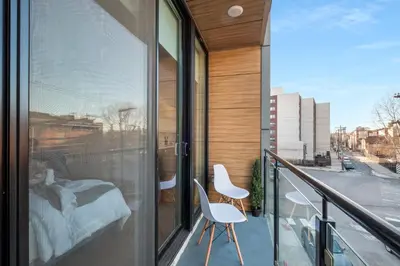 a balcony with two chairs and a bed on it at Skyline Studio - Modern Comfort Pool Access in Philadelphia