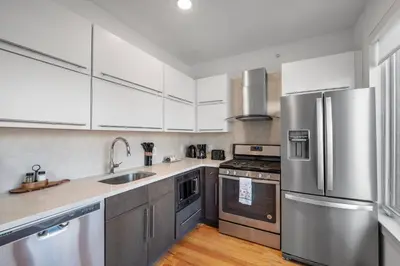a kitchen with white cabinets and stainless steel appliances at Skyline Studio - Modern Comfort Pool Access in Philadelphia