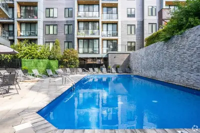 a swimming pool with chairs and a building at Skyline Studio - Modern Comfort Pool Access in Philadelphia