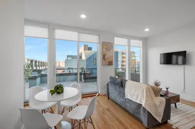a living room with a couch and a table and chairs at Luxury 1BR Loft - Skyline Views Pool Access in Philadelphia