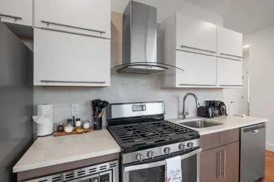 a kitchen with white cabinets and a stove top oven at Luxury 1BR Loft - Skyline Views Pool Access in Philadelphia