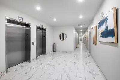 a hallway with white walls and silver doors and marble floors at Luxury 1BR Loft - Skyline Views Pool Access in Philadelphia
