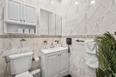 a white bathroom with a toilet and a sink at Skyline Haven Luxe NYC Escape in Jersey City