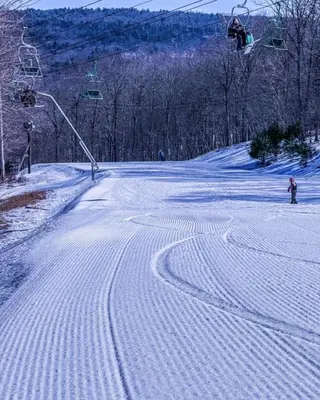 a person riding a snowboard down a snow covered slope at Chalet in Masthope Community in Lackawaxen