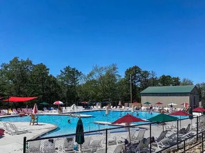 a large swimming pool with chairs and umbrellas at Chalet in Masthope Community in Lackawaxen