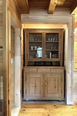 a large wooden cabinet in a room with wooden floors at Waterfront Secluded Log Cabin in Beach Lake