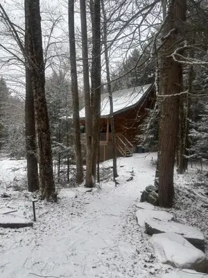 a log cabin in the woods in the snow at Waterfront Secluded Log Cabin in Beach Lake