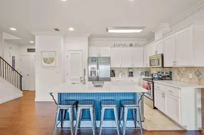 a kitchen with white cabinets and blue bar stools at Casa Del Mar - GOLF CART INCLUDED in Philadelphia
