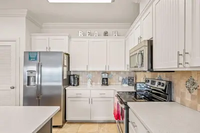 a kitchen with white cabinets and a stainless steel refrigerator at Casa Del Mar - GOLF CART INCLUDED in Philadelphia