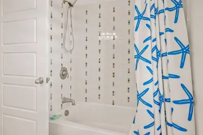 a bathroom with a white tub and a blue shower curtain at Casa Del Mar - GOLF CART INCLUDED in Philadelphia