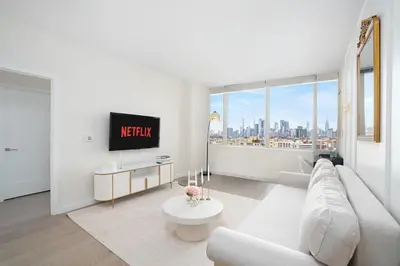 a living room with a white couch and a tv at Midtown View - Minutes to City in Hoboken