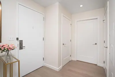 a hallway with two white doors and a vase of flowers at Midtown View - Minutes to City in Hoboken