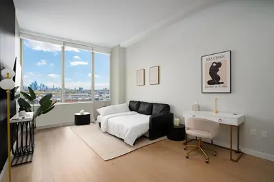 a white bedroom with a bed and a desk and window at Exclusive 1BR Apt with NYC View in Hoboken