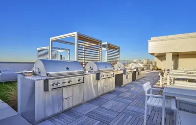 a patio with a row of grill equipment on a deck at Exclusive 1BR Apt with NYC View in Hoboken